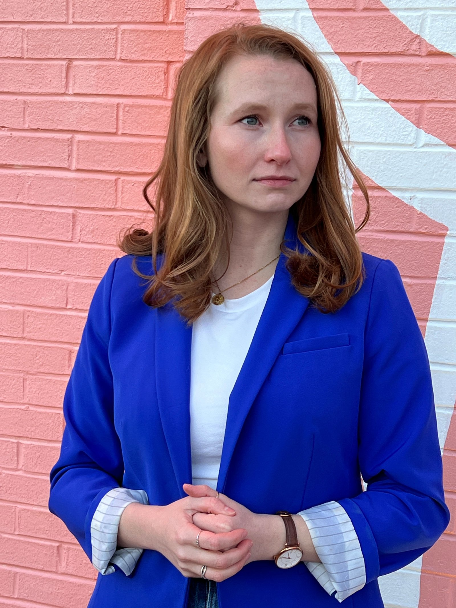Caitlyn Gegen with a determined expression in front of a coral pink wall with white star mural